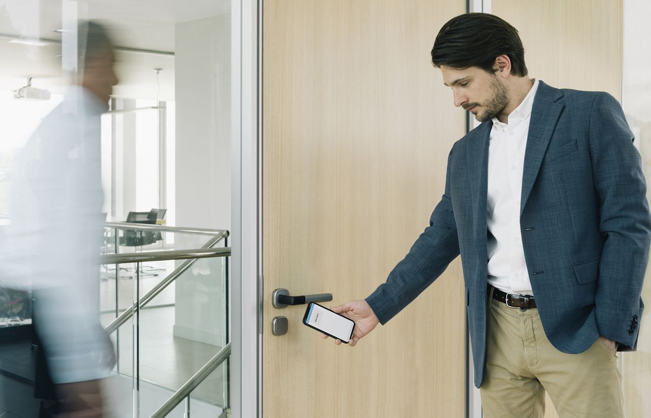 Muž vycházející ze dveří s tabletem v ruce