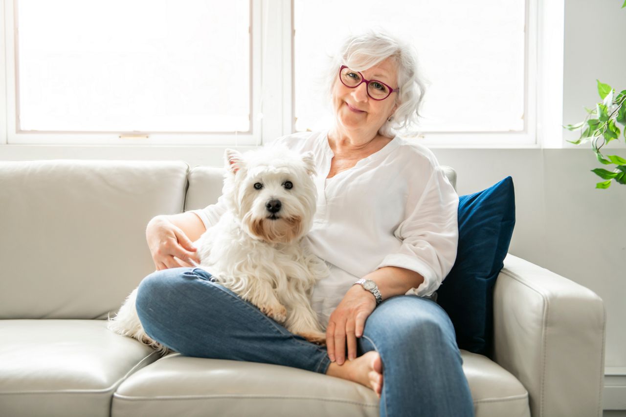 Kvinna som sitter i soffan med sin hund.