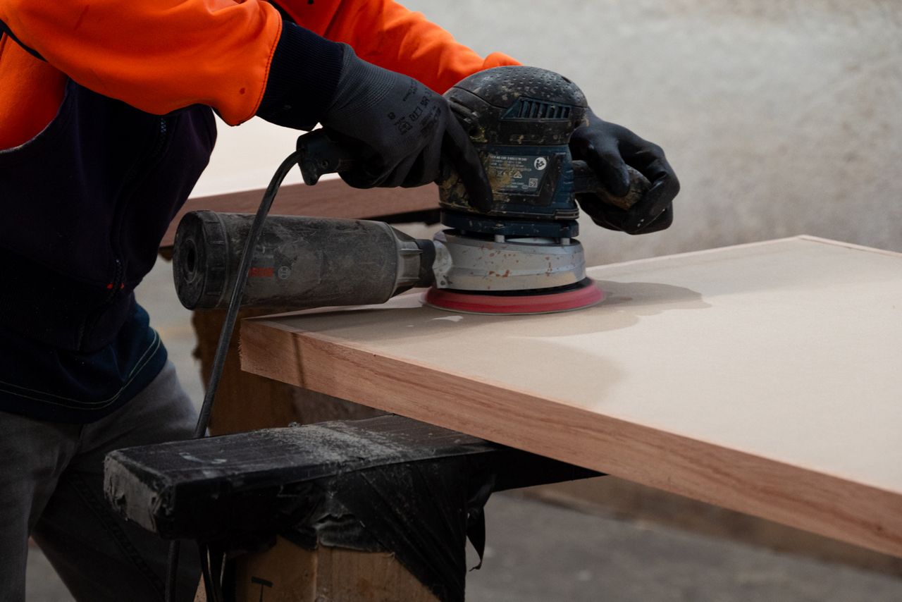 A production worker sanding the face of a door
