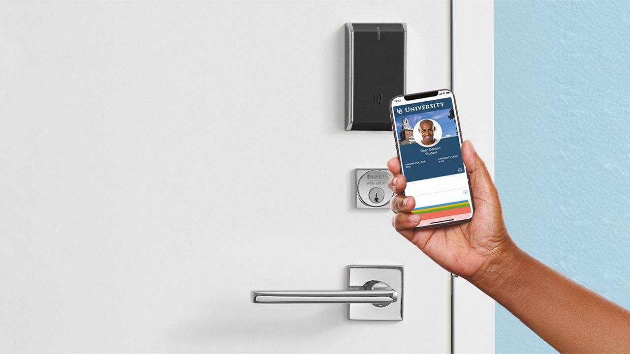 A hand holding a mobile phone credential to a electronically accessed door. 