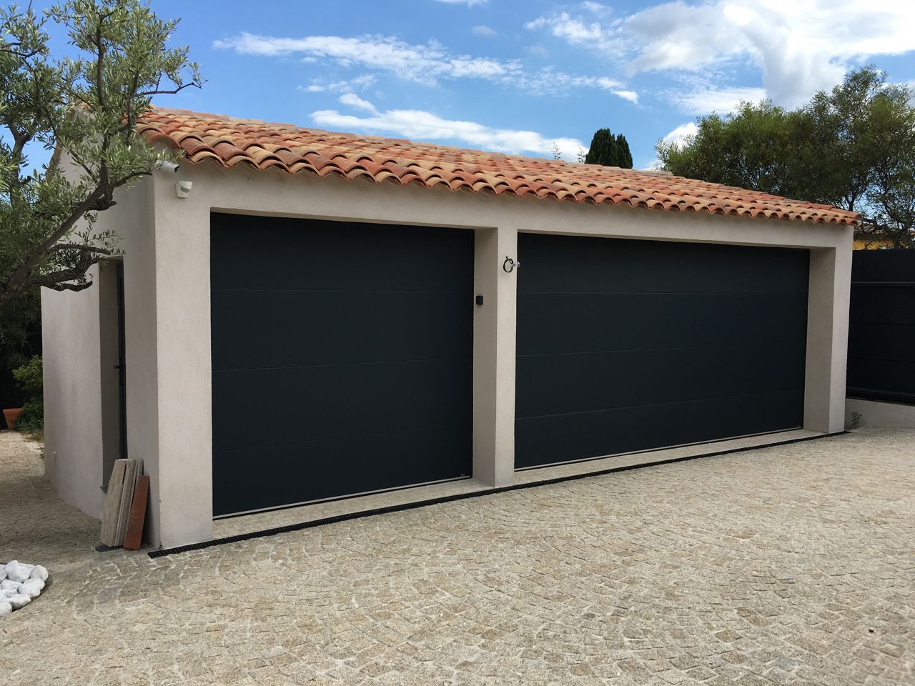 Double garage avec deux portes noires fermées.