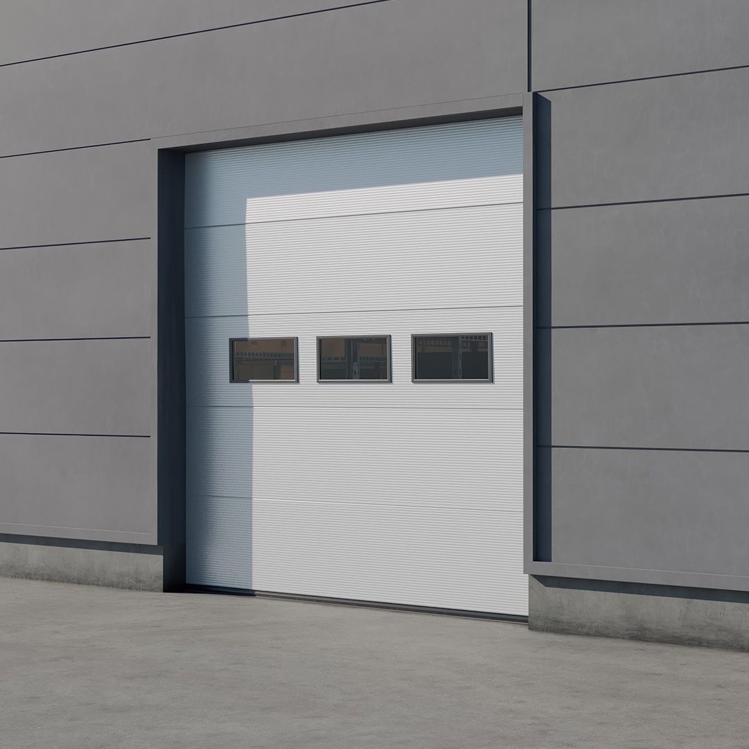 Image: Ușă secțională albă, închisă, pe un clădire industrială gri, cu un șir orizontal de trei ferestre dreptunghiulare.