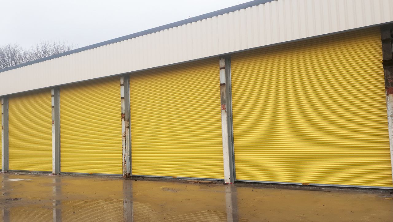 Yellow electric operated roller shutters on a garage building. 