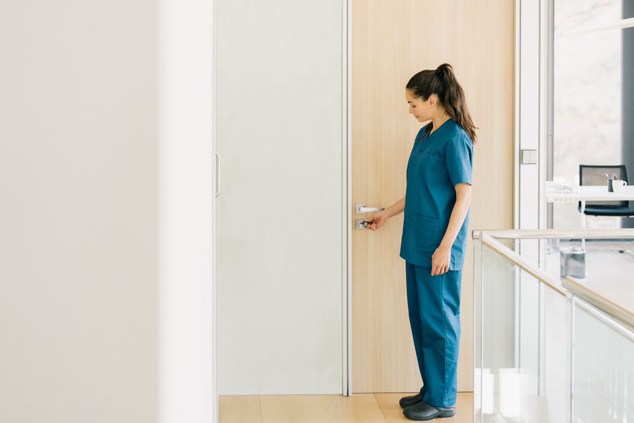 Nurse opening a door in a care environment.