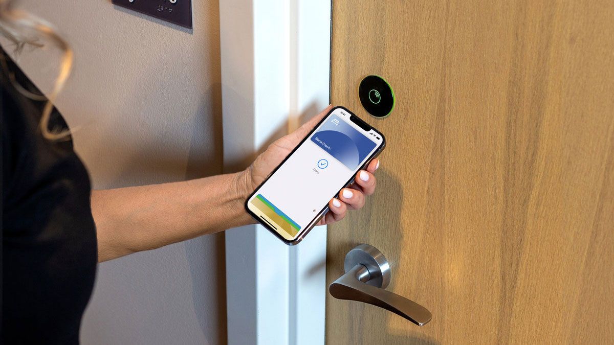 Vingcard essence electronic lock on door while woman uses app to open