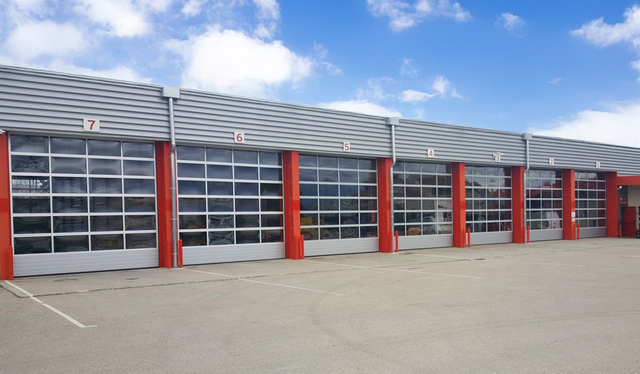 Long red industrial building with several closed panoramic doors.