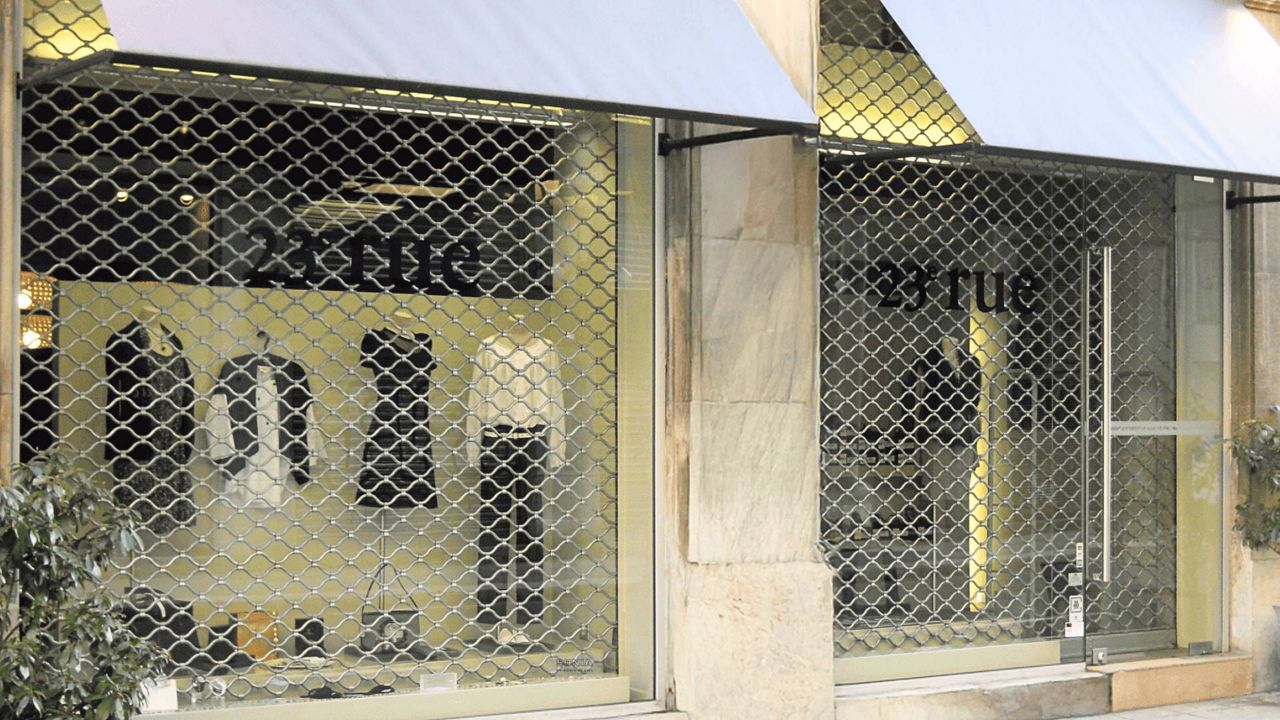 Grille métallique de sécurité à tubes ondulés TUBONDA installée en façade de vitrine de commerce, offrant protection et visibilité intérieure.
