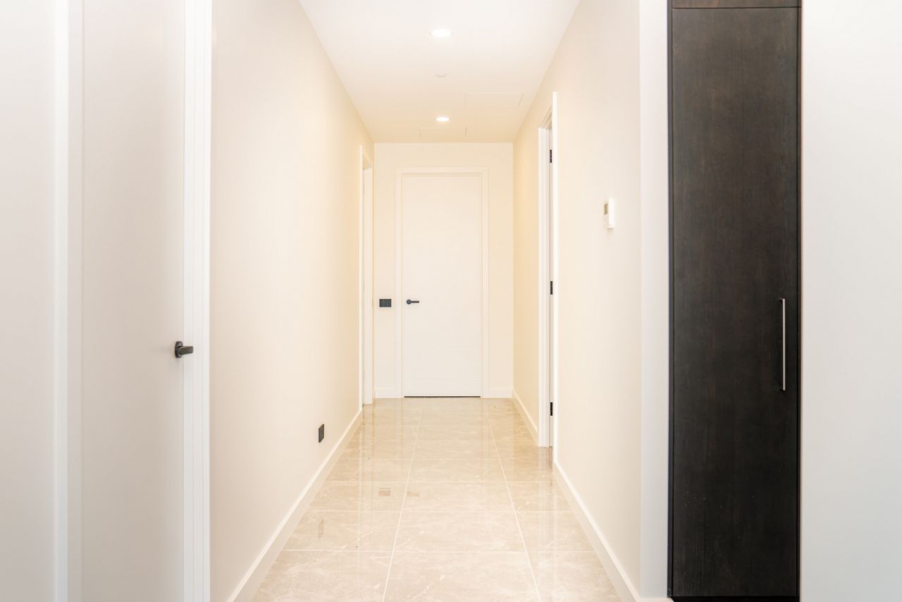 A cream flush panel door in an apartment building hallway.