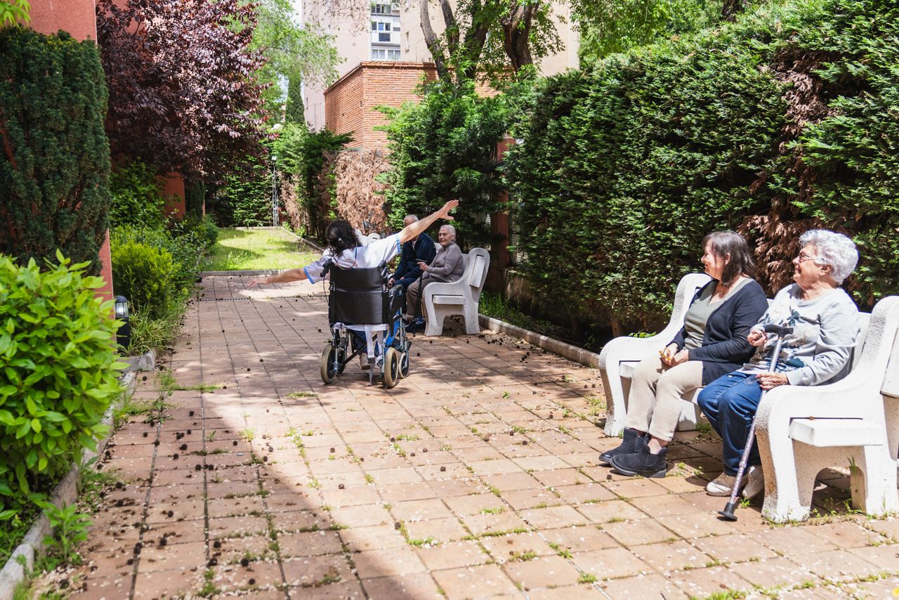 Ældre med handicap nyder en solrig dag udenfor i en park ved et plejehjem.
