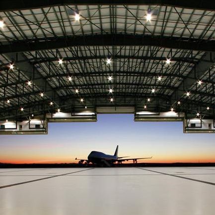 El hangar del aeropuerto, con un avión en la apertura de la puerta con una puesta de sol en la parte trasera