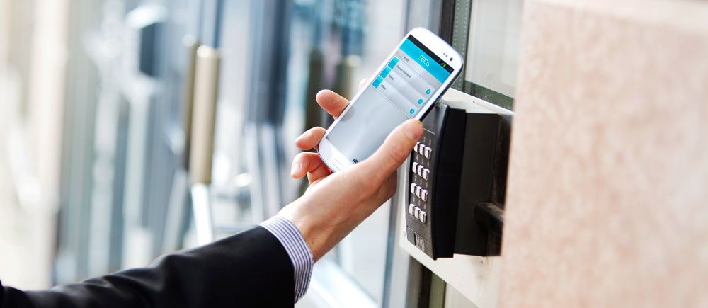 Ruka držící chytrý telefon nad čtečkou karet