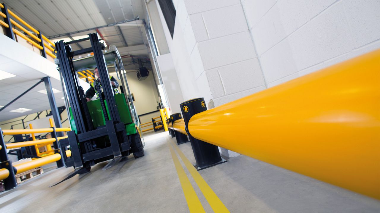 Barreira Flexível de Tráfego Simples eFlex, com tubo amarelo de alta visibilidade e postes pretos de proteção, segregando rotas de veículos e protegendo estruturas