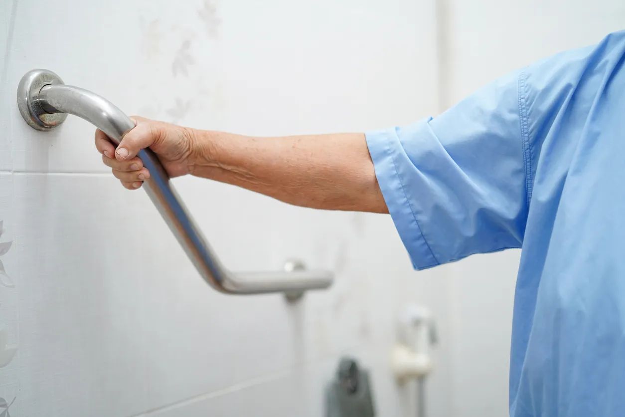 Patient holding on a toilet railing