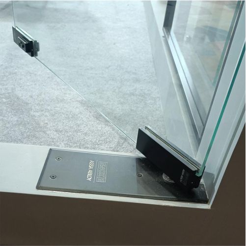 Floor Spring installed under a heavy glass door showing controlled movement and stable support.
