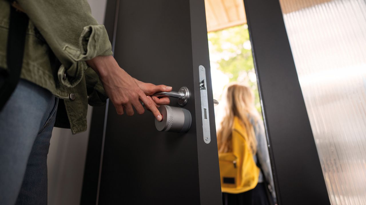 Un homme quitte la maison en utilisant le bouton KeySense sur la serrure intelligente Yale Linus® L2 Lite.