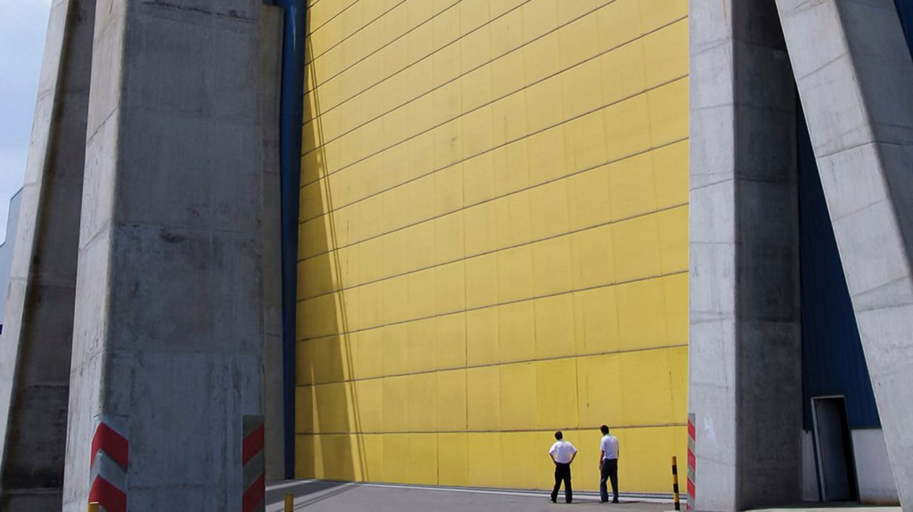 A big yellow door with two workers looking up at it. 