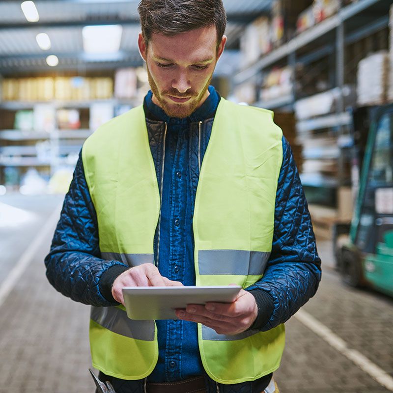 Man in safety vest holding a screen device