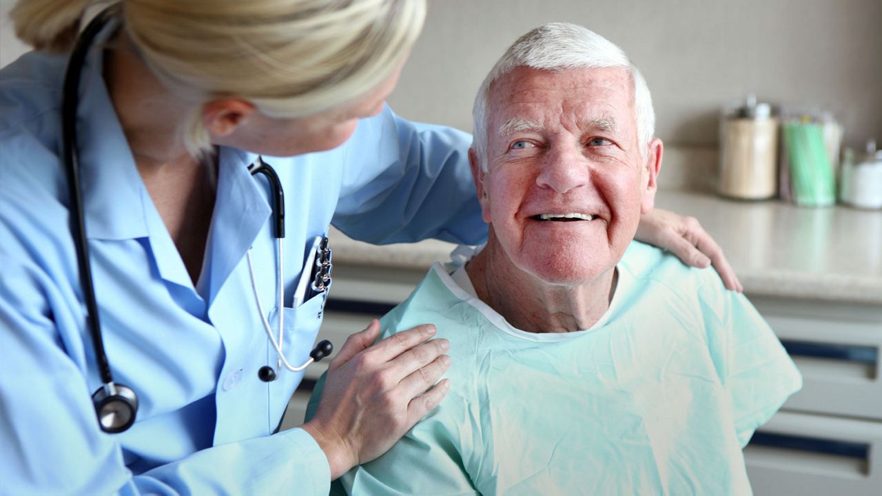 A man in green hosptila clothes looking up on a female doctor, smiling. 