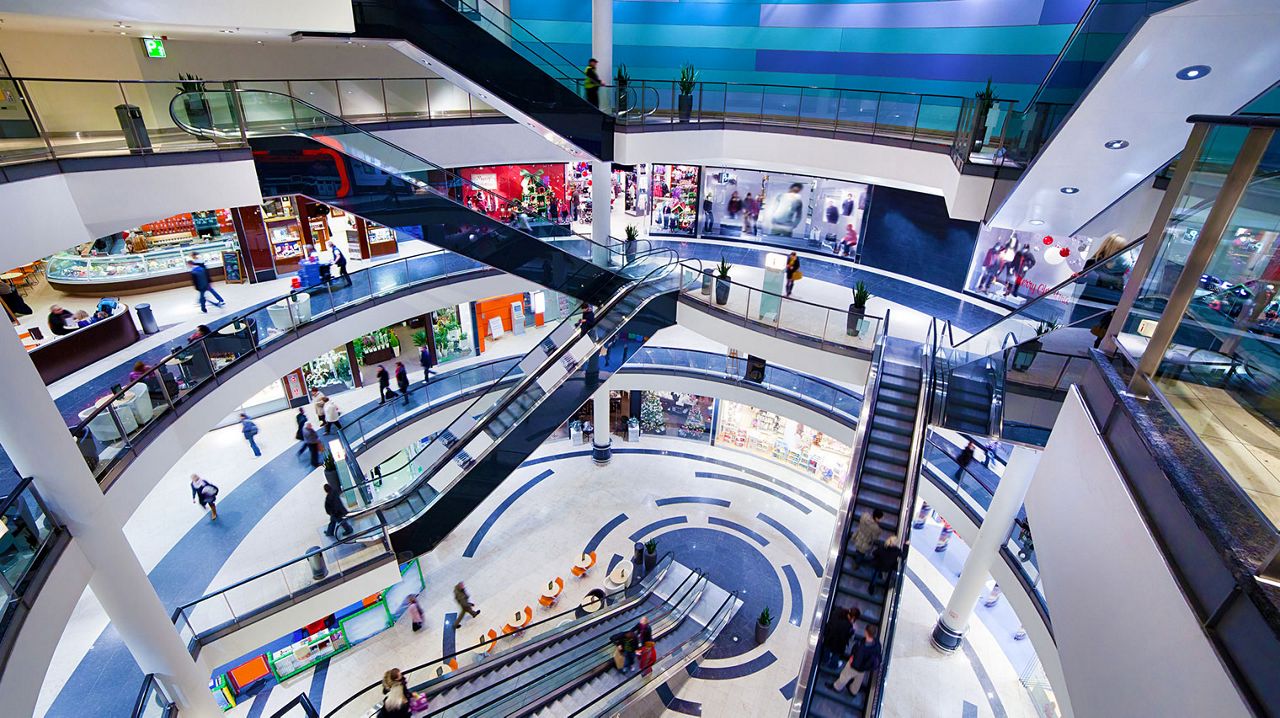 Un centro comercial con seis escaleras mecánicas y gente caminando por el centro comercial