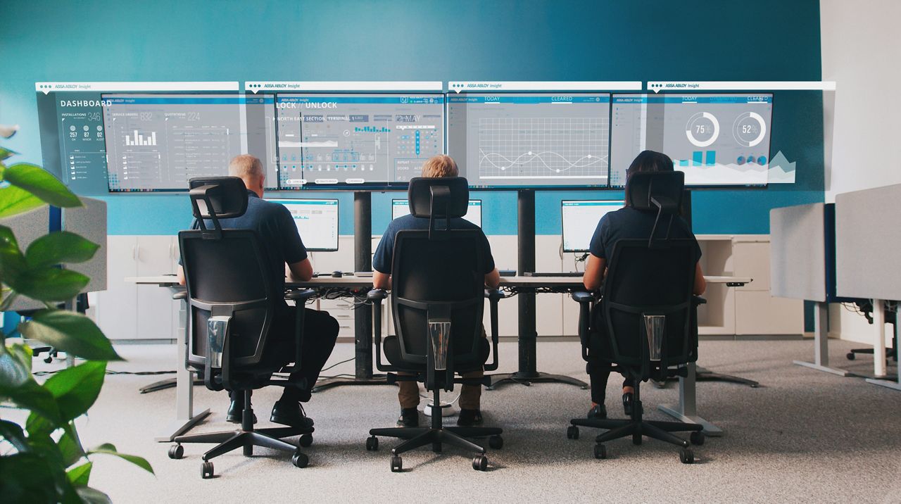 3 Personen, die vor großen Computerbildschirmen sitzen