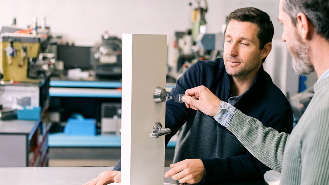 En låssmed visar en kund hur hen installerar ett lås.