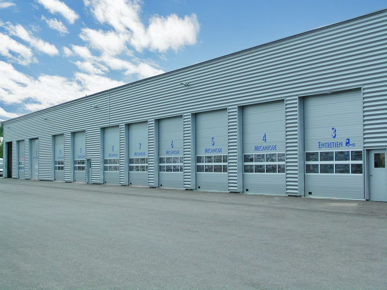 Industrial building taken from the side, with closed grey doors with glazed sections.