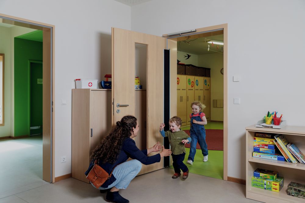 Kinderen lopen door deur met deurpomp met Cam-Motion technologie
