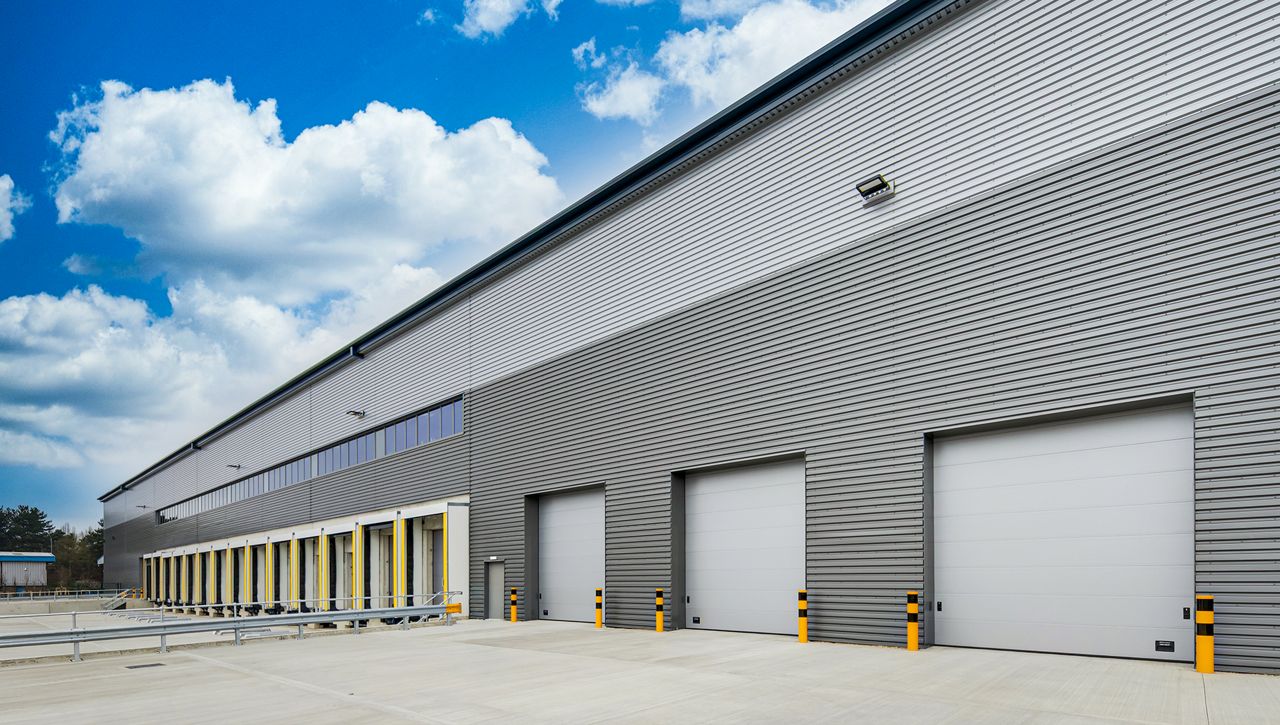A row of three Crawford OH1042P level access door, with a row of ASSA ABLOY loading bay equipment to side of the sectional doors