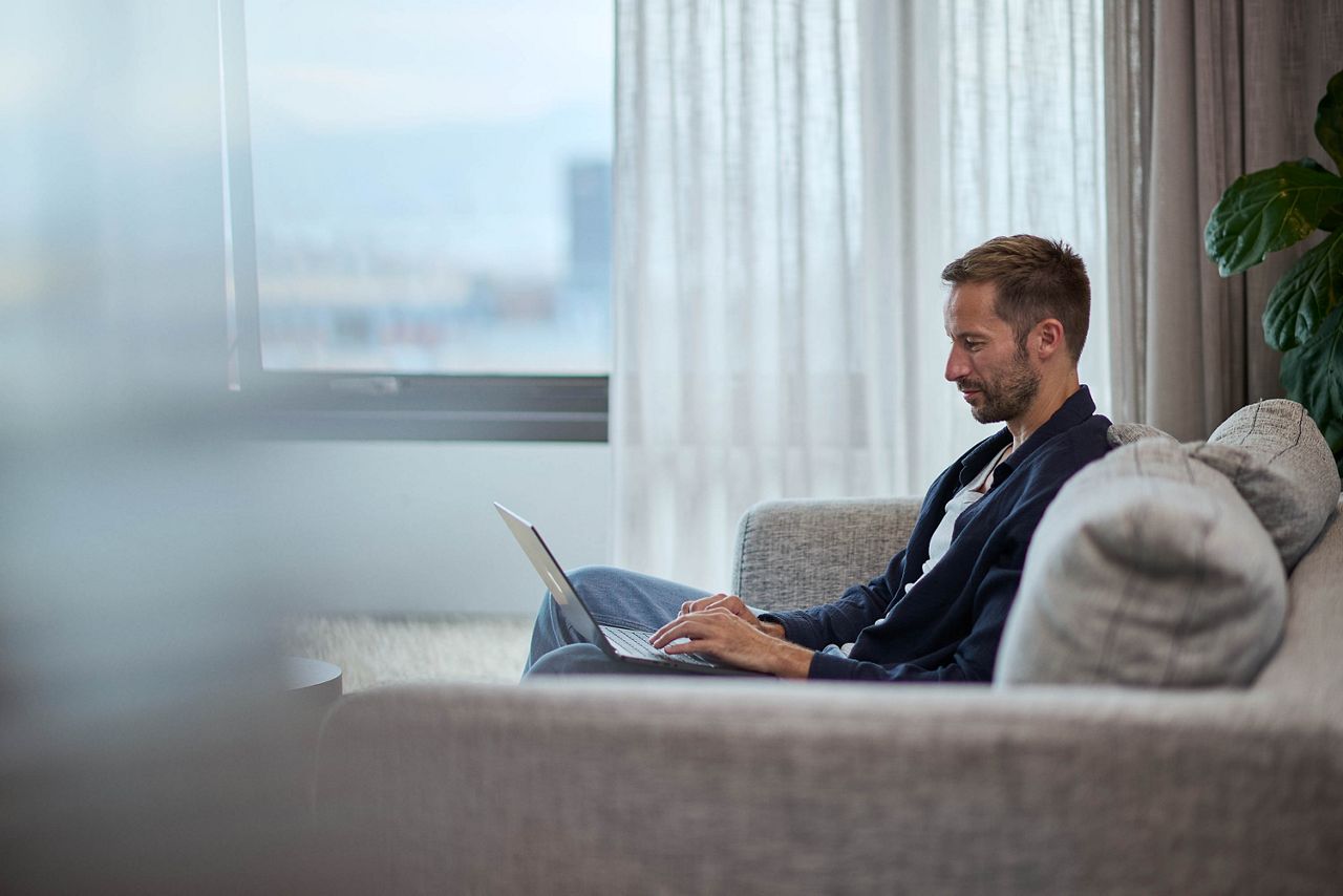 Man sitting in a sofa working on his laptop.