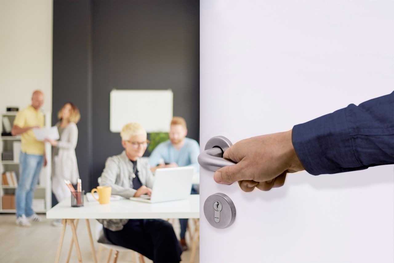 Ruka otevírající bílé dveře za stříbrnou kliku