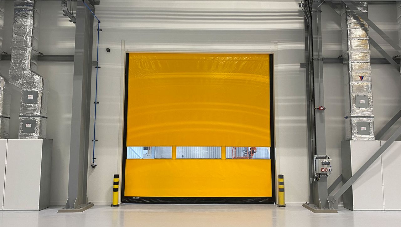 An yellow internal high-speed door with with vision panel in a warehouse. 