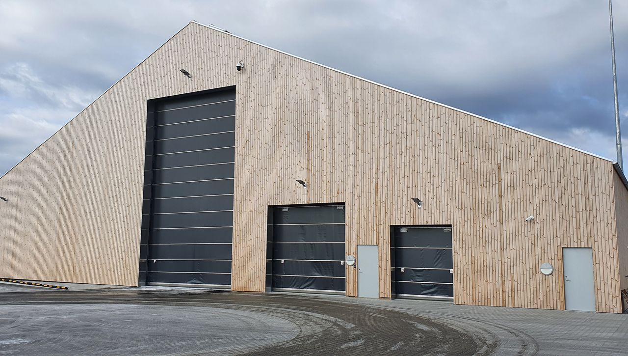 Image: Three ASSA ABLOY VL3116 vertical lifting fabric door in row at a maintenance depot