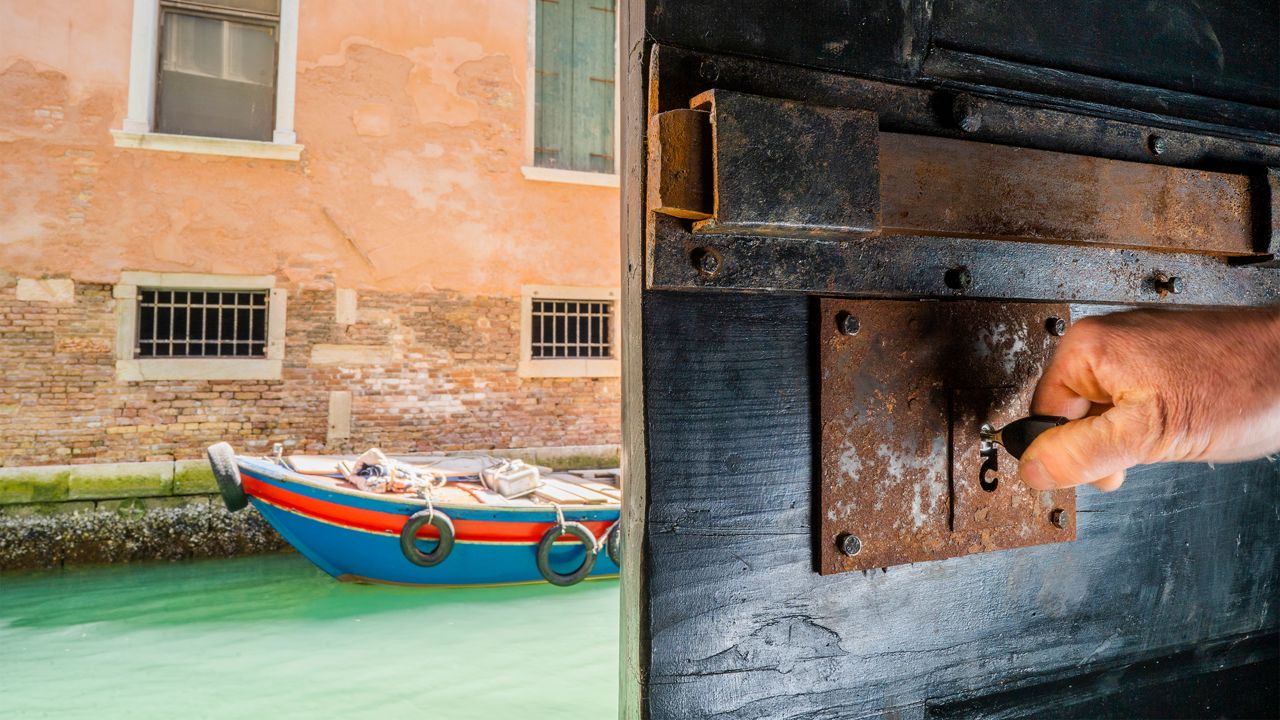 PROTEC2 key on a lock on an open door, with a Venice waterway in the back