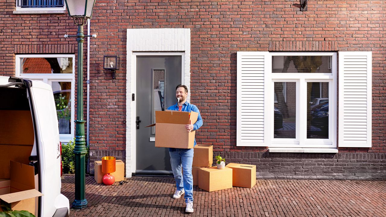 Man is aan het verhuizen met sleutel van huis in zijn mond