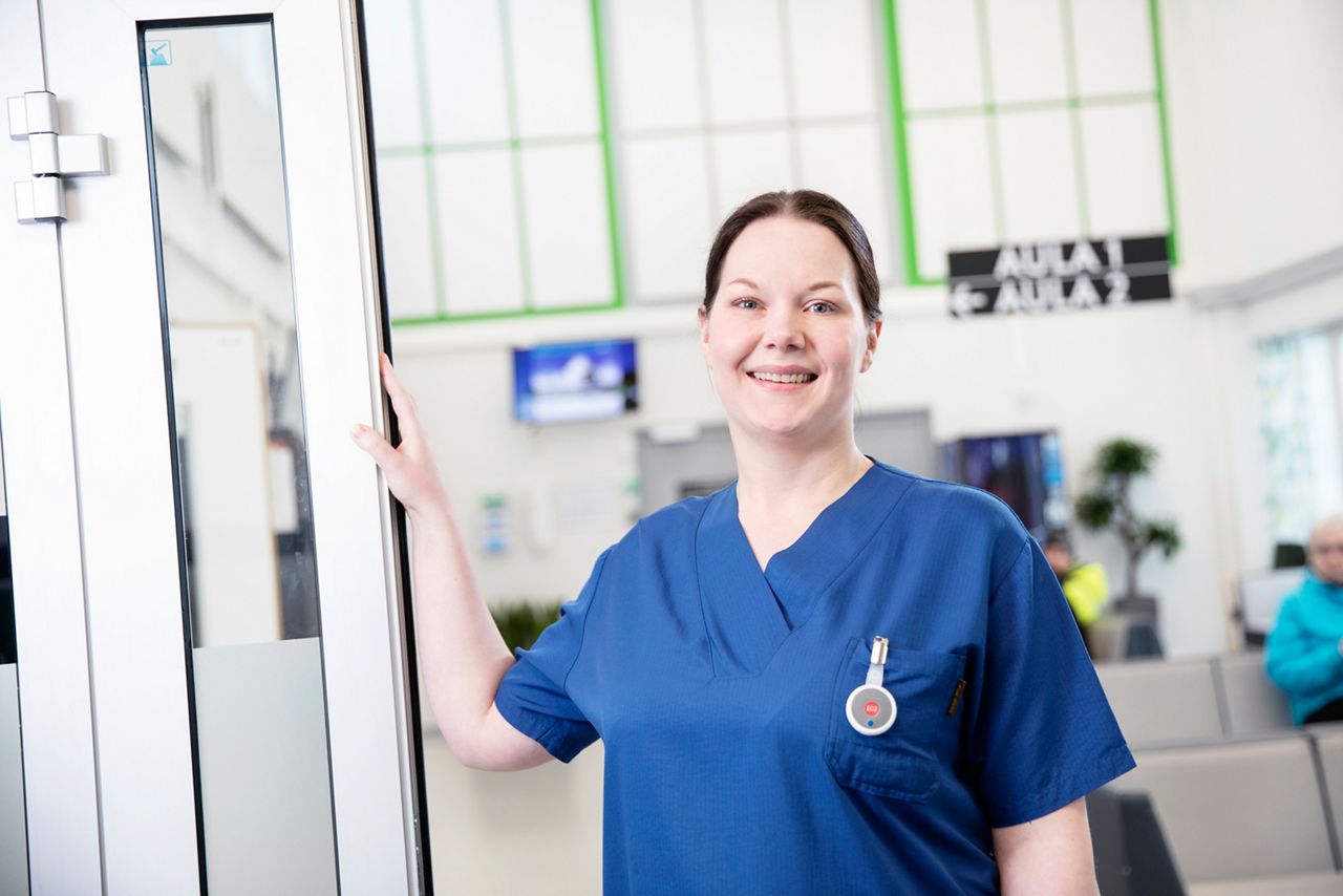 Nurse standing in a doorway in a hospital lobby.