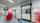 A white high speed door inside a factory environment wiht white walls, a worker walking past with red boxes on a cart.