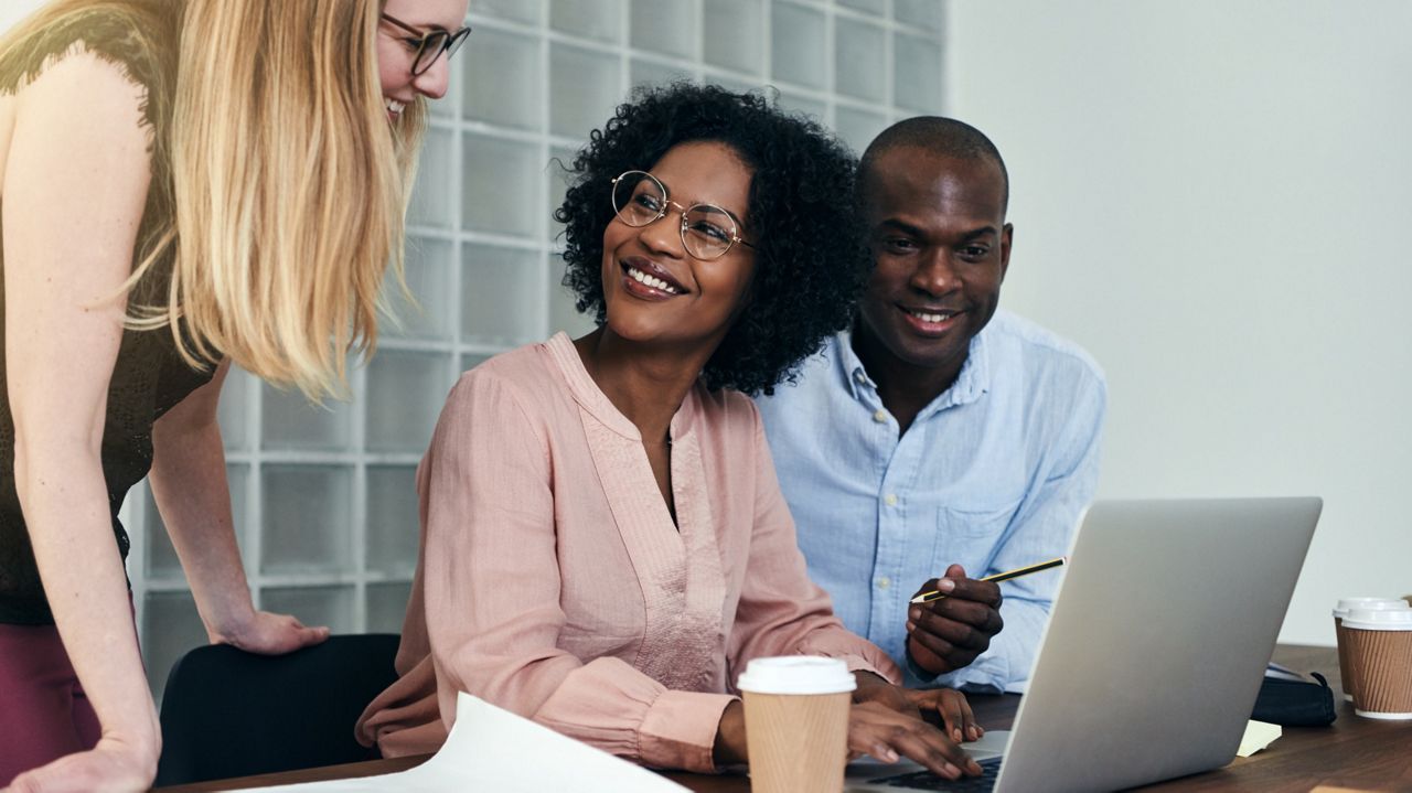 Three people, two women and a man, at a laptop.