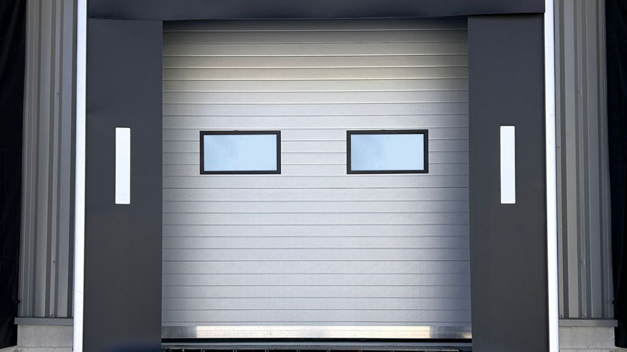 Porte sectionnelle industrielle grise avec deux hublots rectangulaires intégrés installée sur un quai de chargement.
