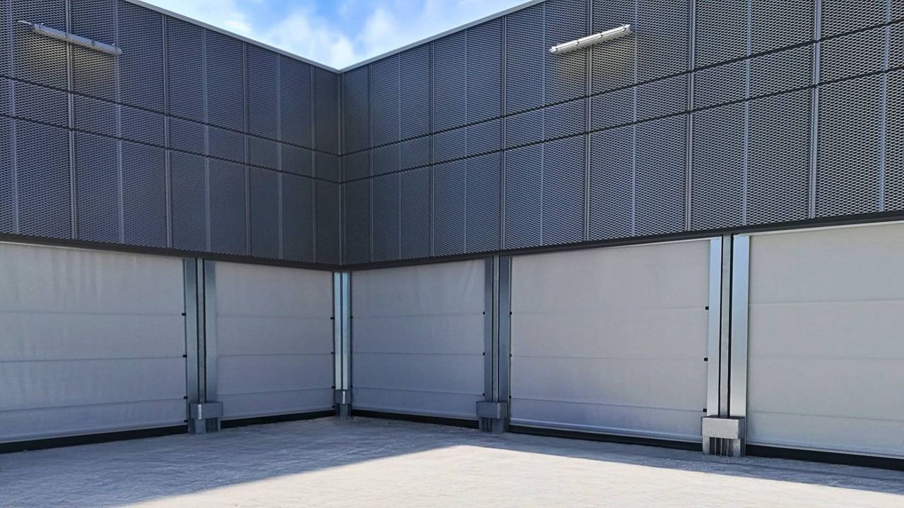 Porte souple rapide à enroulement blanche modèle JET R installée sur un bâtiment industriel, vue d'extérieur.