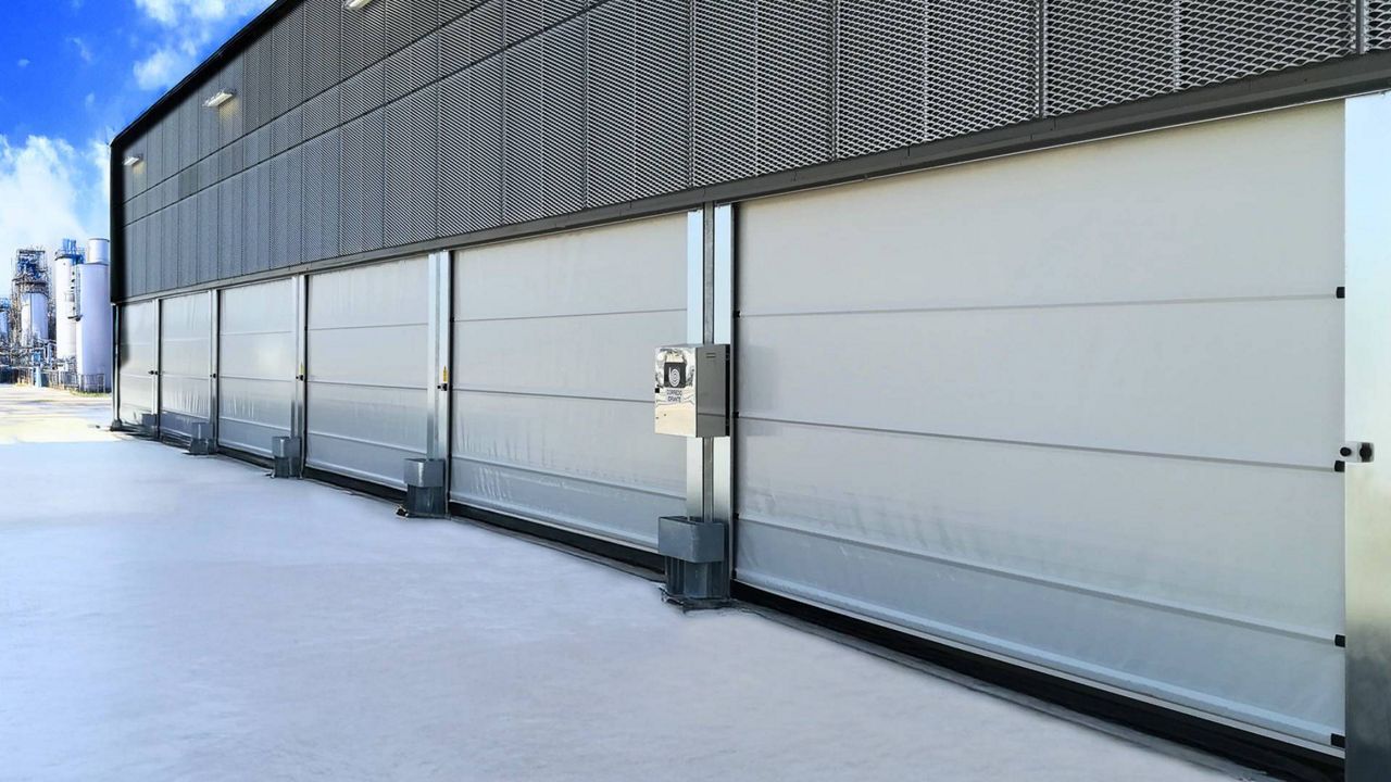Portes souples rapides à enroulement blanches et fermées, installées sur un bâtiment dansune zone industrielle.