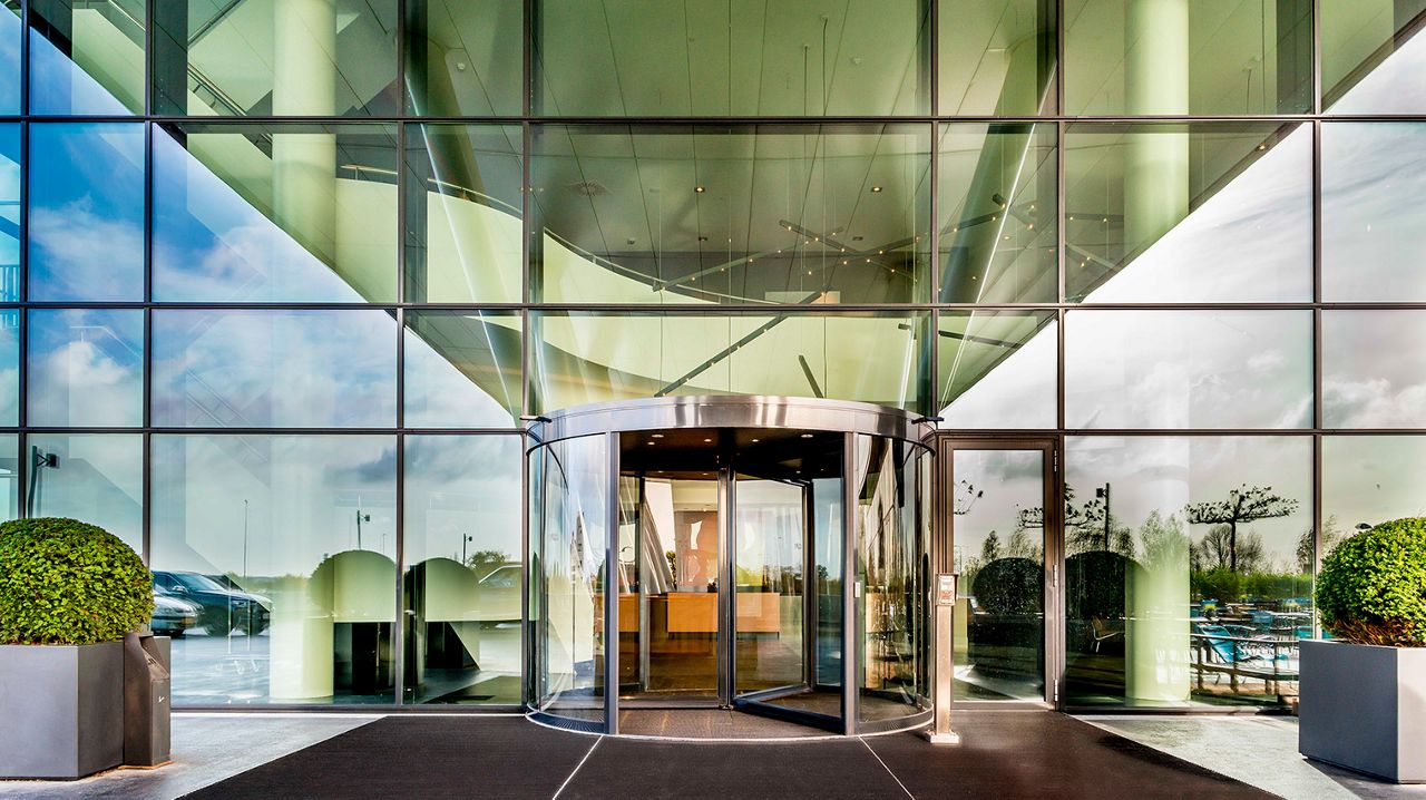 A smiling couple walking through revolving doors.
