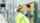 En tekniker med säkerhetsutrustning (hjälm, skyddsglasögon, väst) inspekterar en takskjutport i en industribyggnad och manövrerar kontrollboxen för att analysera ett fel.