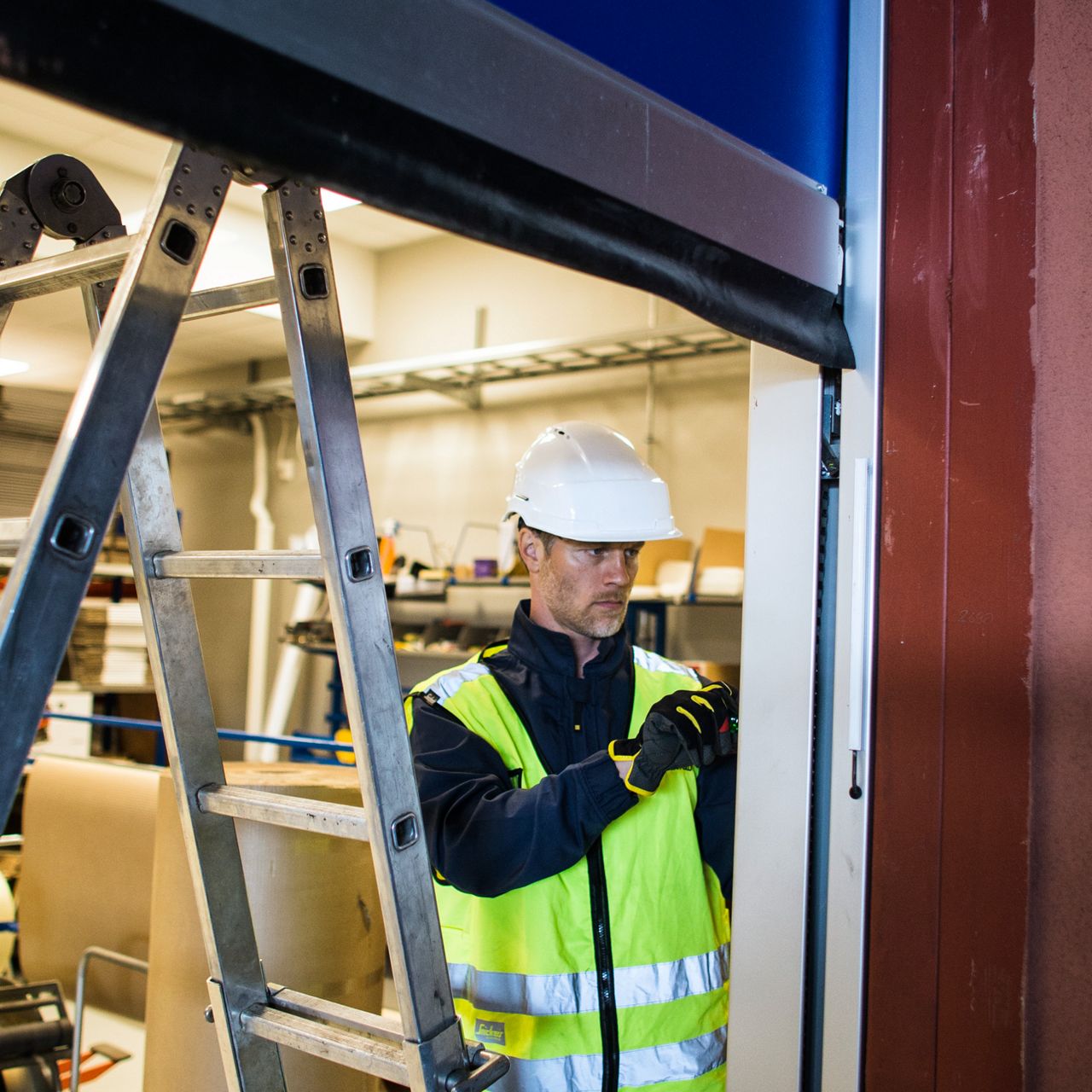 ASSA ABLOY Techniker repariert ein Schnelllauftor bzw. Rolltor.