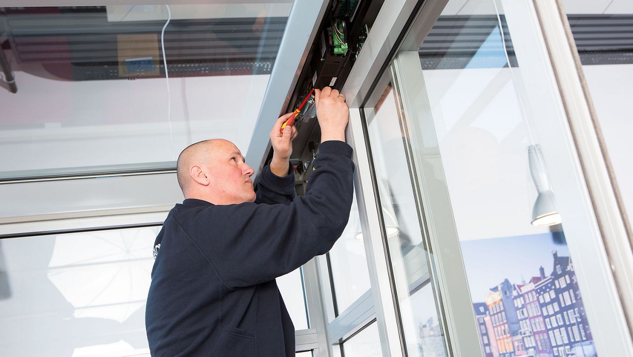 Servisní technik opravující dveřní pohon automatických dveří