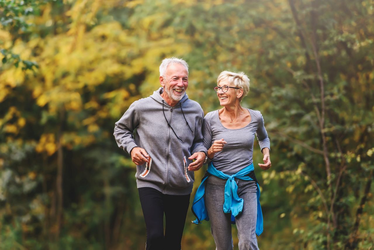 Senior couple jogging smiling and enjoyoing the nature.