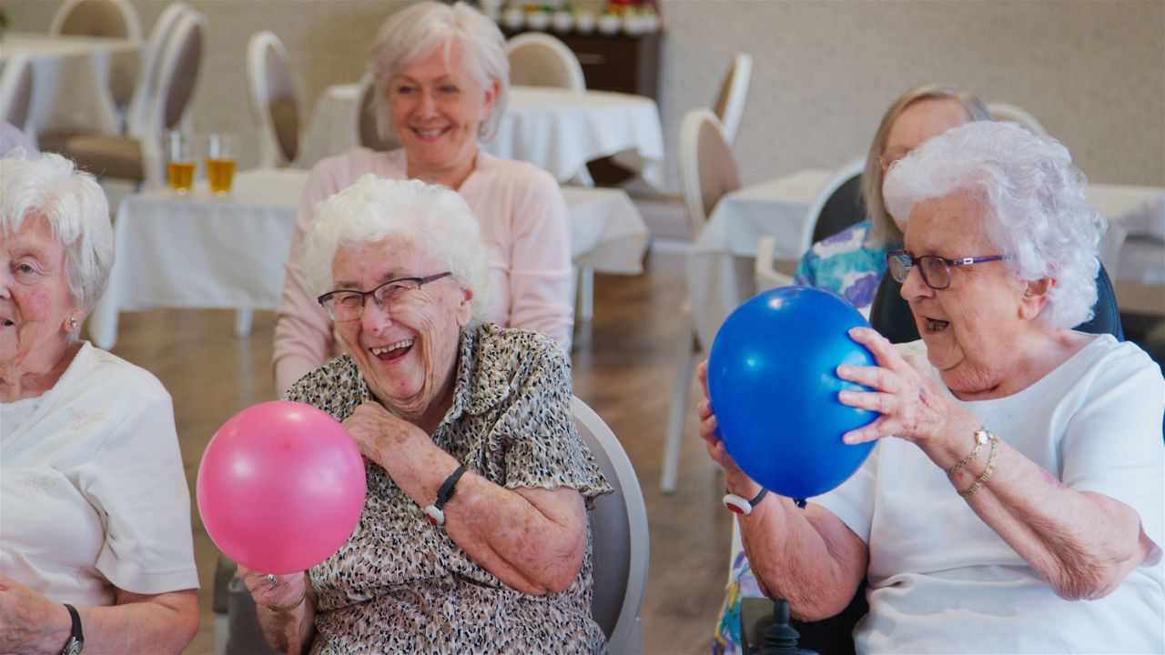 Äldre damer leker med färgglada ballonger.