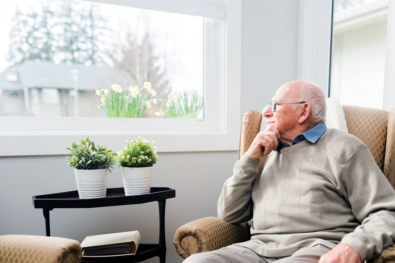 Ældre mand kigger ud af vinduet på plejehjem.