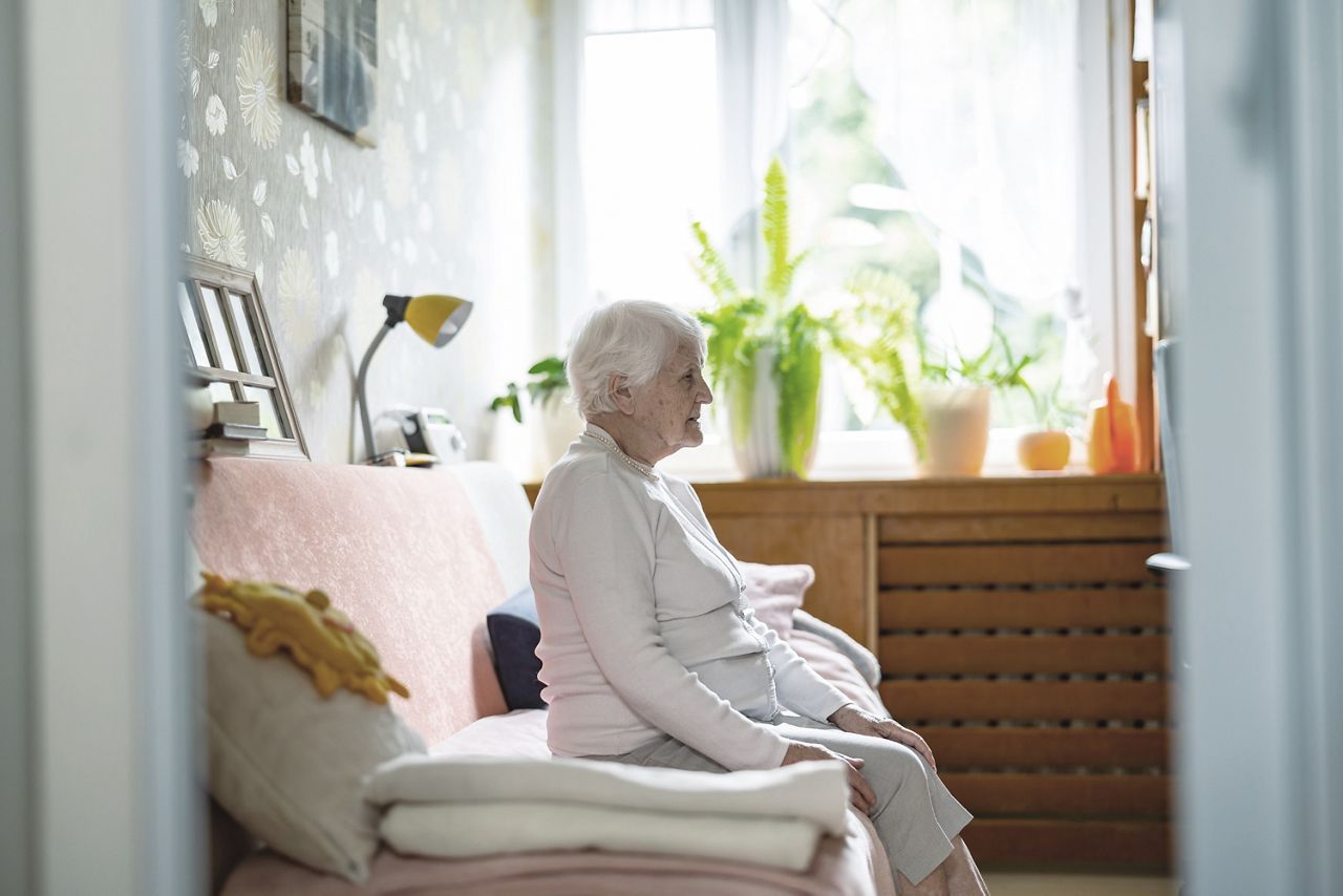 Oudere vrouw zit op haar slaapbank.