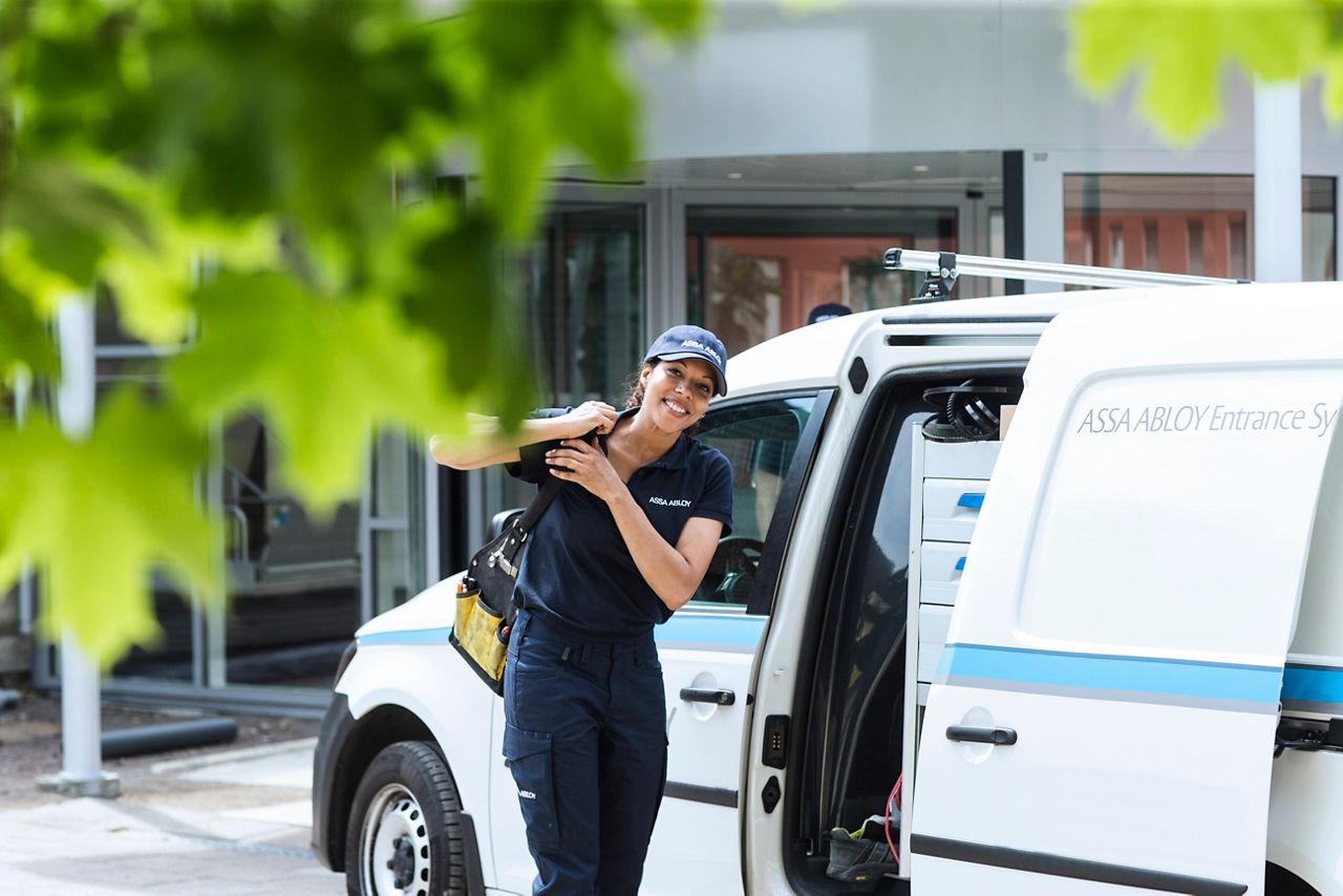 Service woman talking something out of a white ASSA ABLOY service truck. 