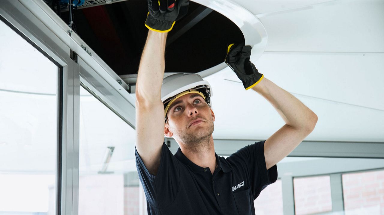Un techniicen de maintenance Assa Abloy qui contrôle une porte.